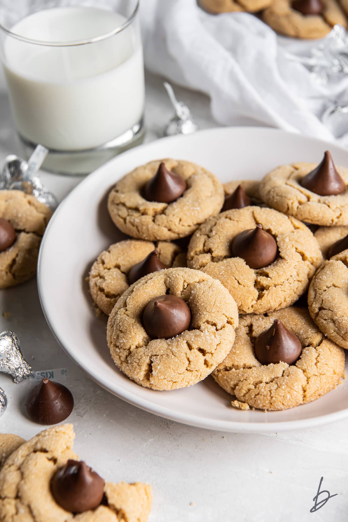 plate of peanut butter blossoms in front of glass of milk.