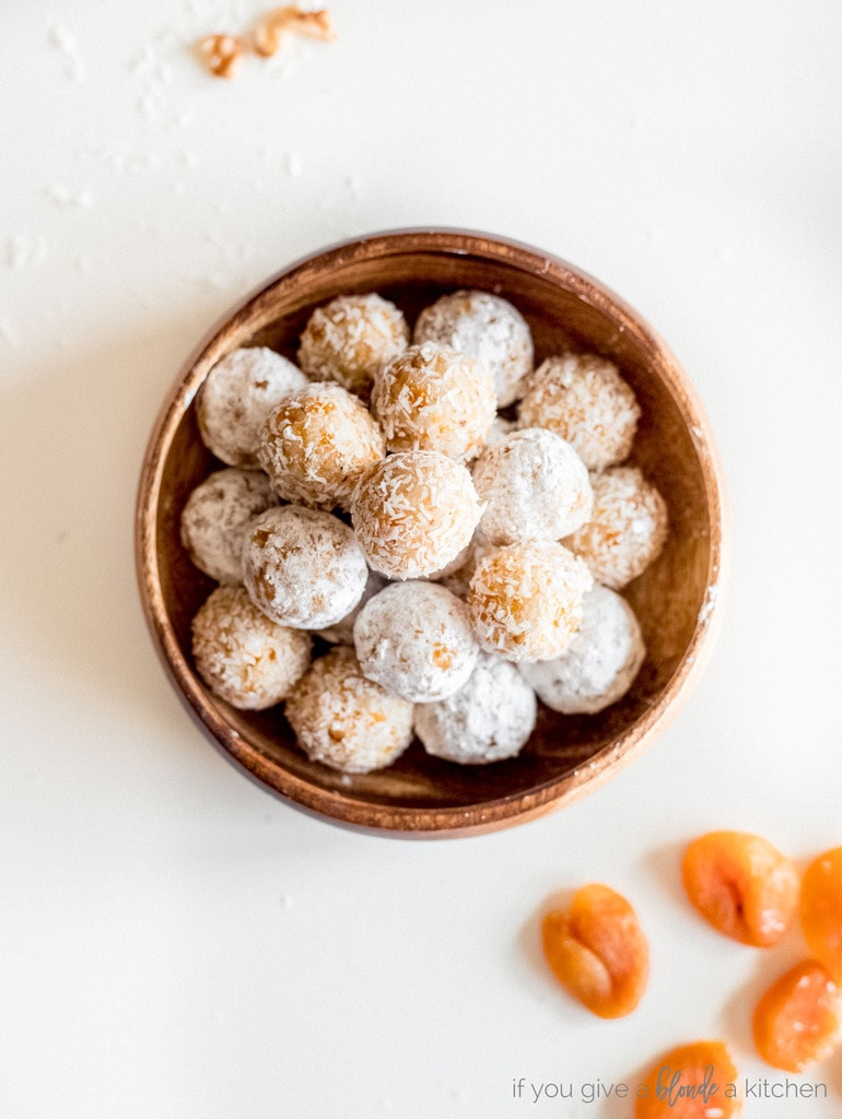 coconut apricot balls in wooden bowl on white surface