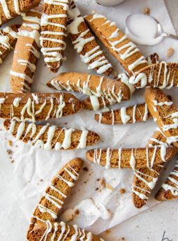 white chocolate drizzled gingerbread biscotti scattered over wrinkled wax paper