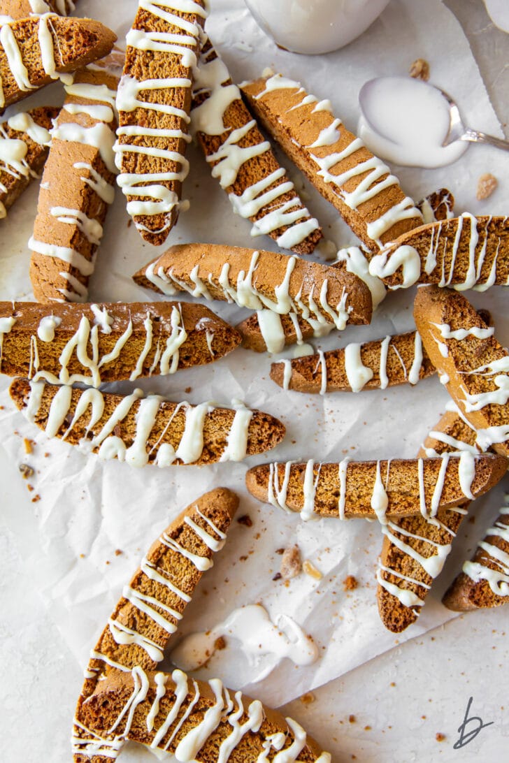 white chocolate drizzled gingerbread biscotti scattered over wrinkled wax paper