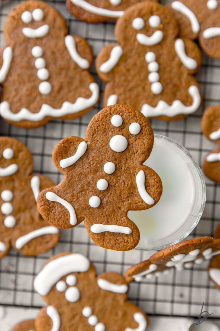 gingerbread man cookie balancing on glass on milk with more cookies around glass