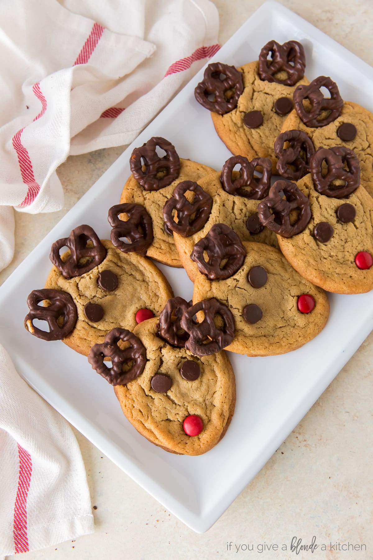peanut butter reindeer cookies with pretzel antlers, chocolate chip eyes, and red m&m nose