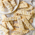 scandinavian almond bars topped with drizzle and slivered almonds in a pile on crinkled parchment paper.