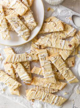 scandinavian almond bars topped with drizzle and slivered almonds in a pile on crinkled parchment paper