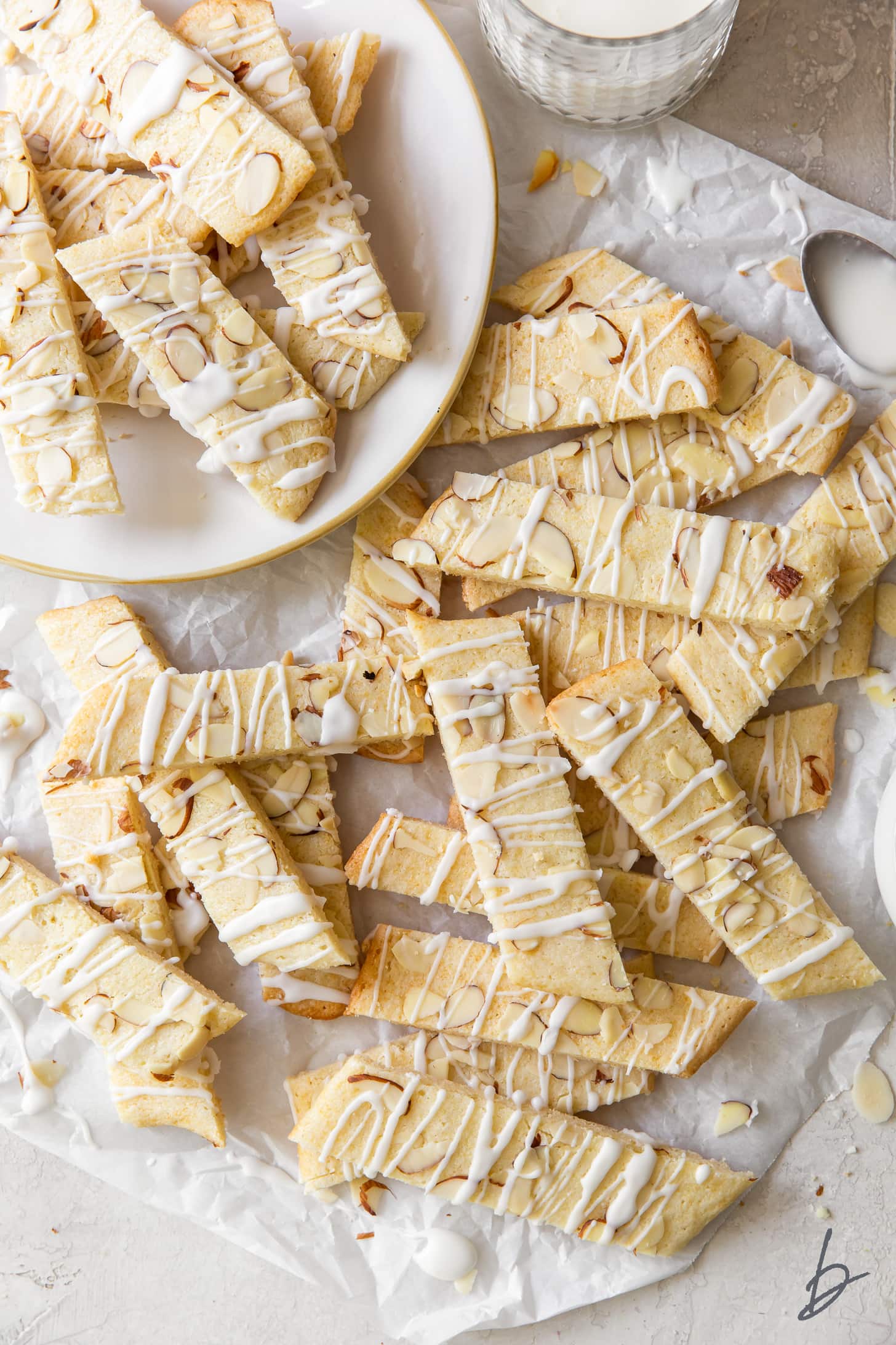 scandinavian almond bars topped with drizzle and slivered almonds in a pile on crinkled parchment paper.