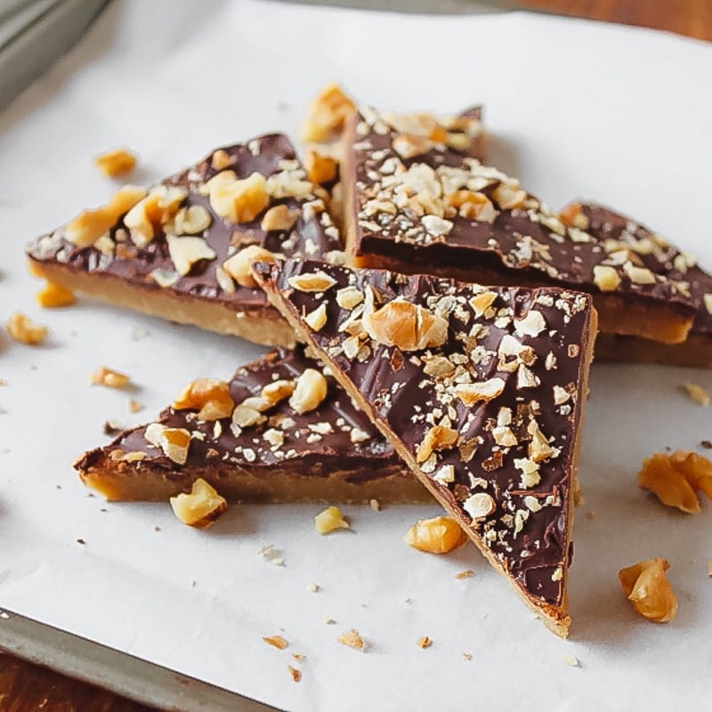 toffee triangles on parchment paperwith broken pies of nuts on top