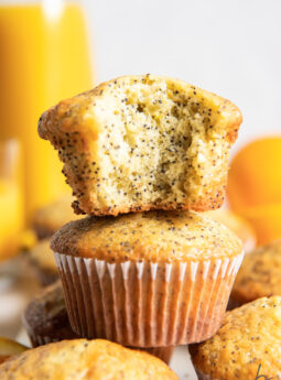 orange poppy seed muffin with a bite stacked on top of another muffin