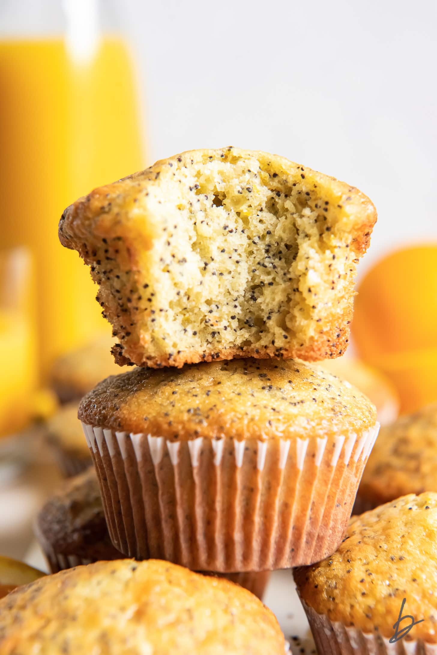 orange poppy seed muffin with a bite stacked on top of another muffin
