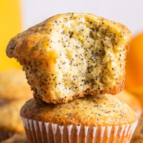 orange poppy seed muffins with a bite on top of another muffin