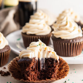 a bite taken out of guinness cupcake with bailey's frosting on paper cupcake liner.