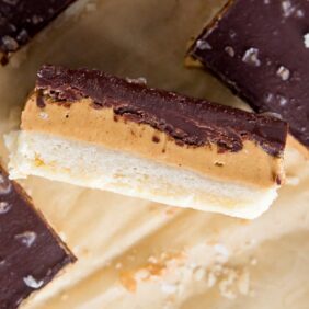 peanut butter chocolate bar on its side showing layers of shortbread crust, peanut butter and chocolate
