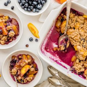 peach blueberry crisp on baking dish and servings in two bowls