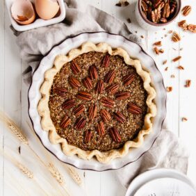 pecan pie in a ceramic pie dish with pecan halves on top arranged to radiate out