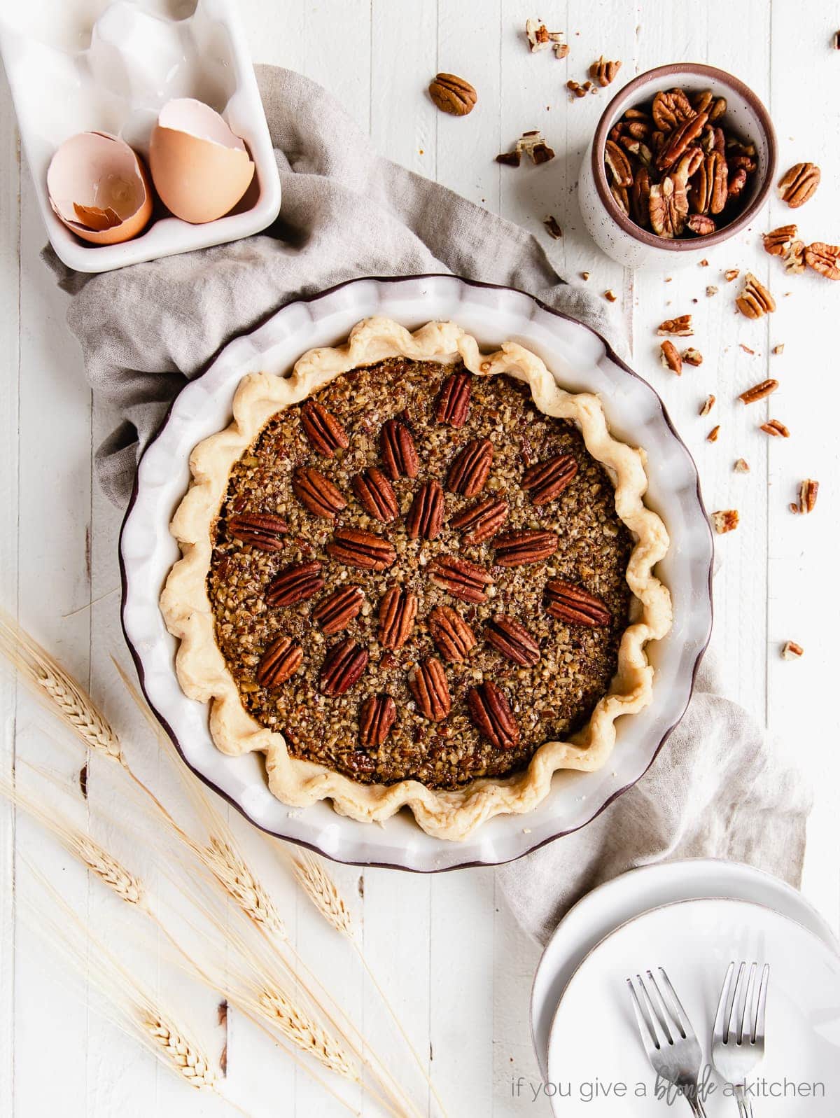 pecan pie in a ceramic pie dish with pecan halves on top arranged to radiate out