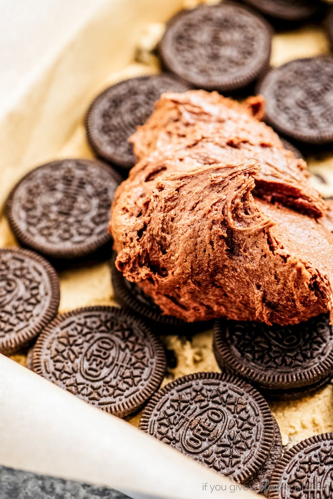 brownie batter spread on top of oreos and cookie dough in baking pan