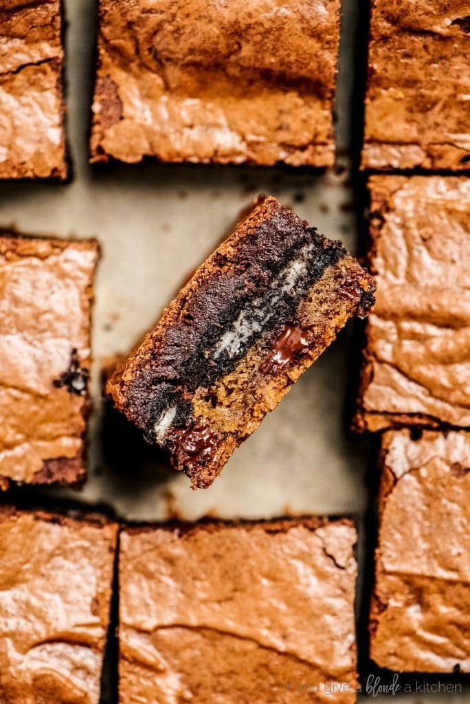 side of slutty brownie showing layers of cookie dough and oreo in pan of brownie squares