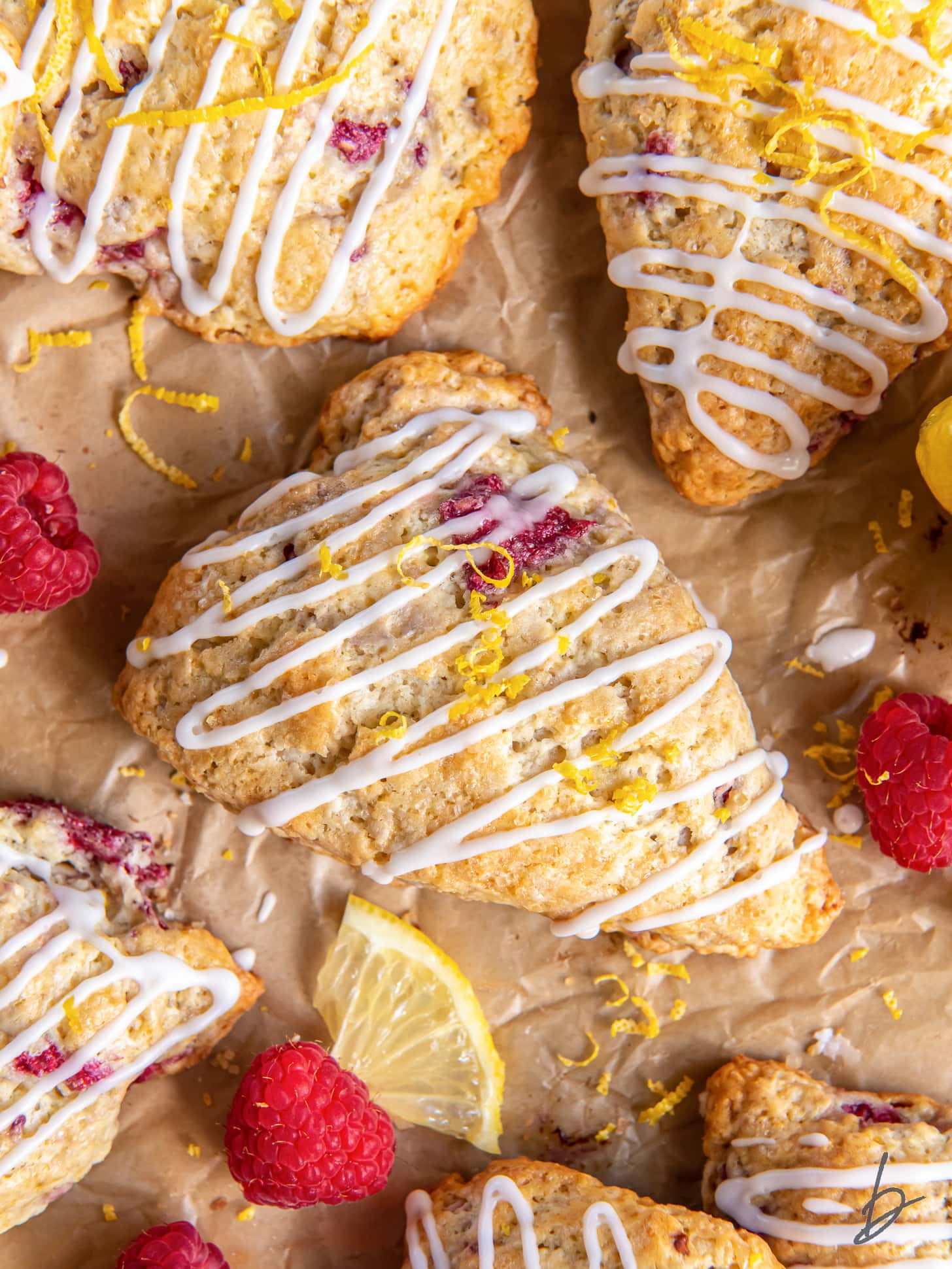 lemon raspberry scones with lemon glaze on parchment paper.