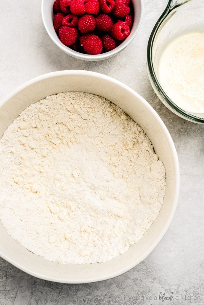 bowl of flour butter mixture, glass measuring cup of milk, bowl of raspberries