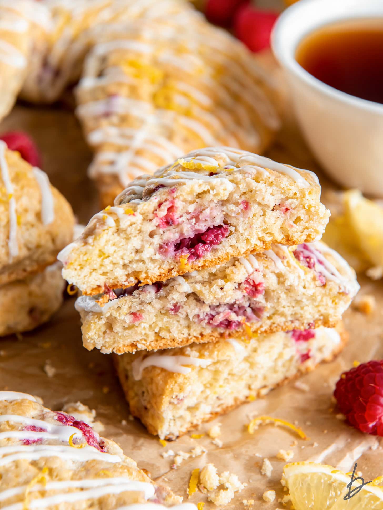 raspberry scones cut in half and stacked on top of each other showing flaky layers and raspberries inside.