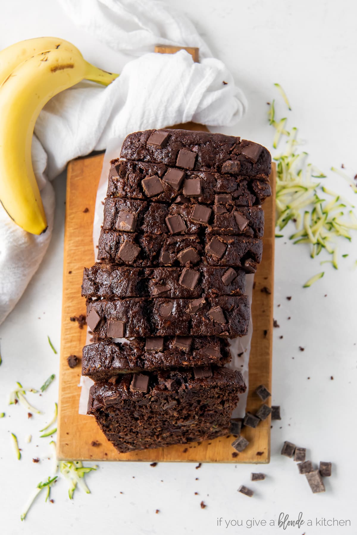 loaf of chocolate zucchini banana bread cut into slices on wood cutting board