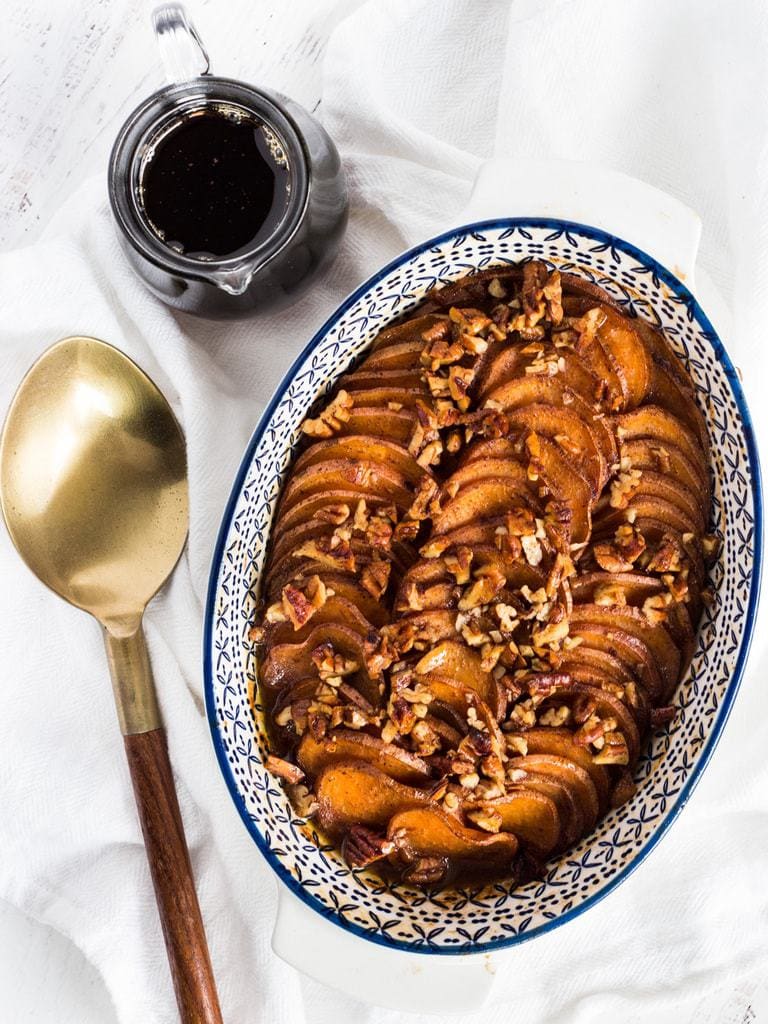 bourbon maple sweet potatoes in a casserole dish next to a serving spoon.