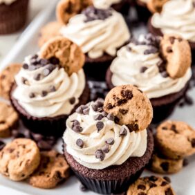 plate of cookie dough frosting cupcakes topped with mini chocolate chips and mini chocolate chip cookies