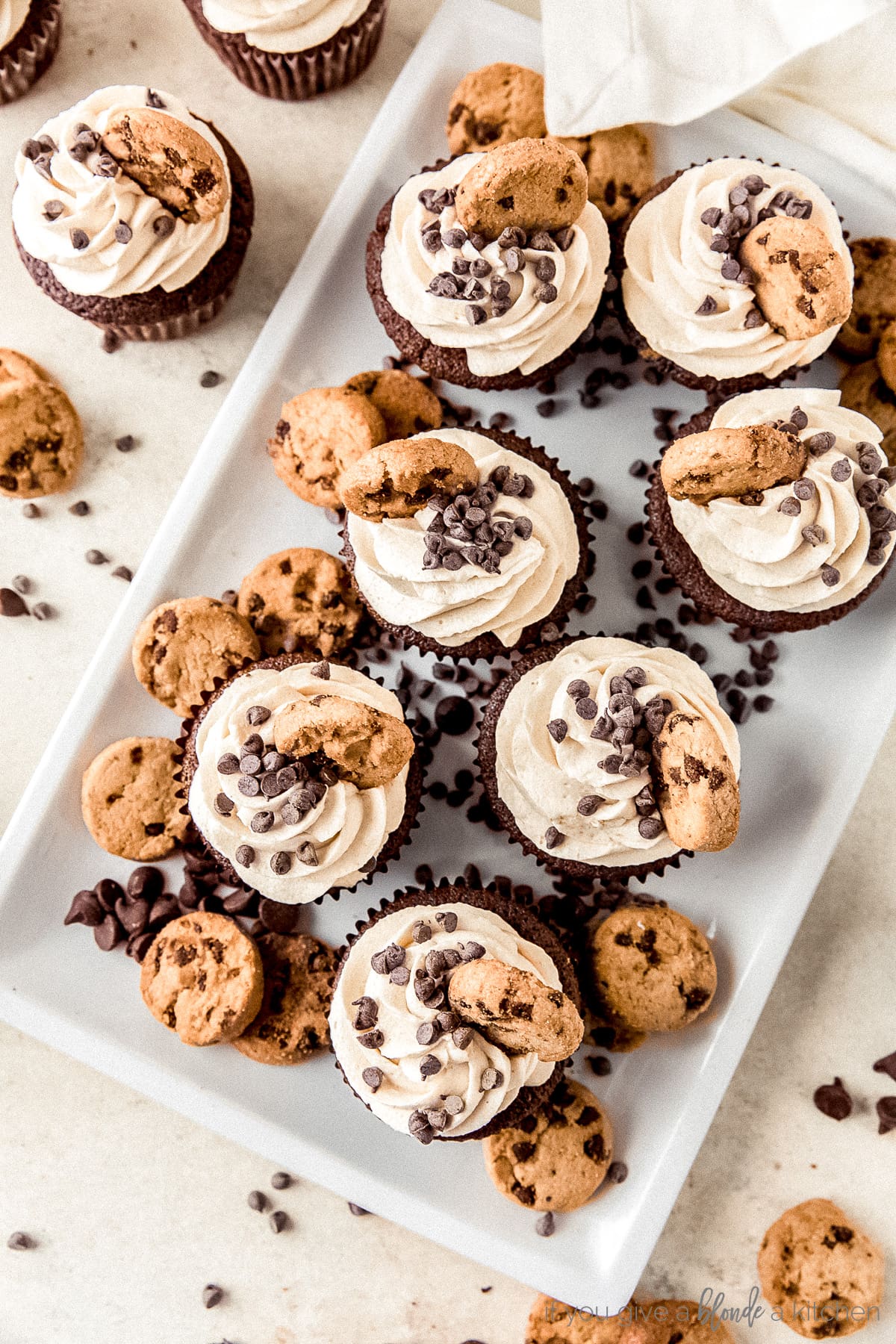 cookie dough frosting cupcakes, mini chocolate chips, mini chocolate chip cookies on rectangular white plate