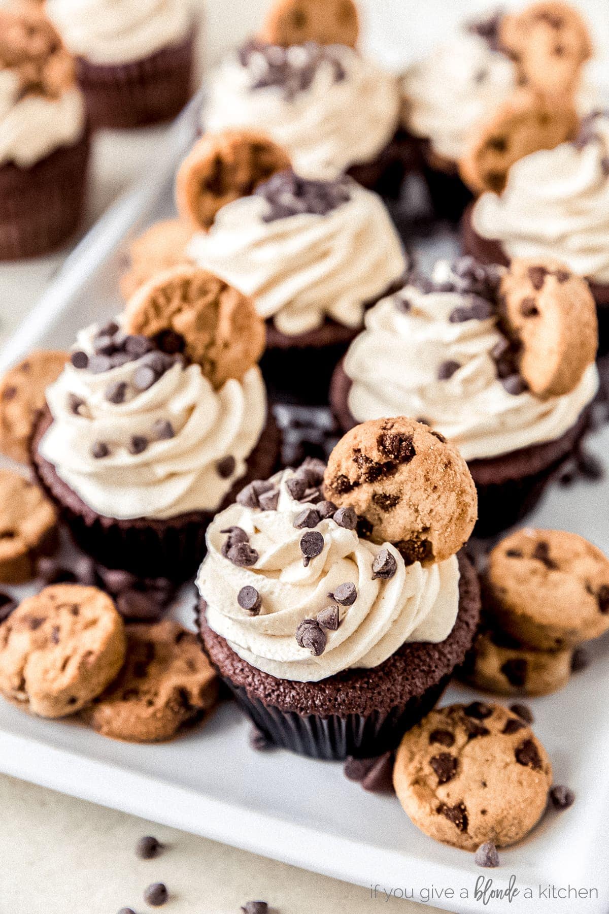 plate of cookie dough frosting cupcakes topped with mini chocolate chips and mini chocolate chip cookies