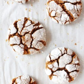 gingerbread crinkle cookies coated in powdered sugar on parchment paper