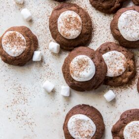 hot cocoa cookies topped with marshmallows halves and dusted with cocoa.