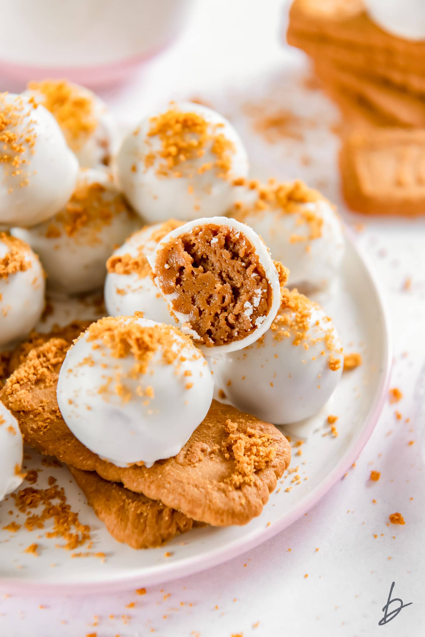 plate of white chocolate covered biscoff truffles with one truffle cut in half