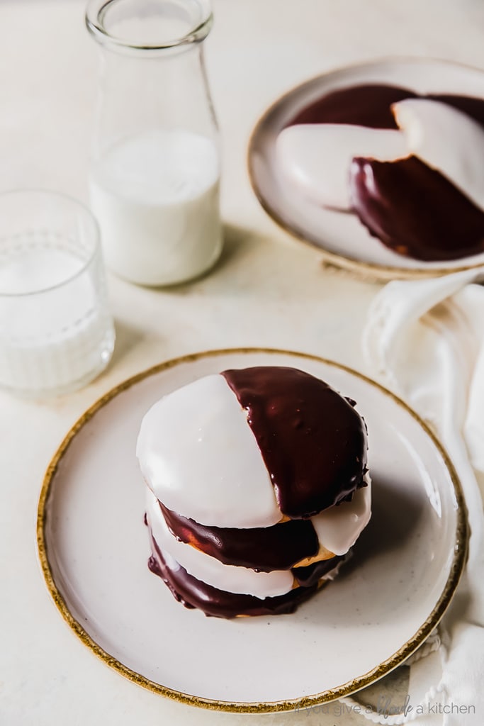 stack of black and white cookies on round plate with bottle of milk behind plate