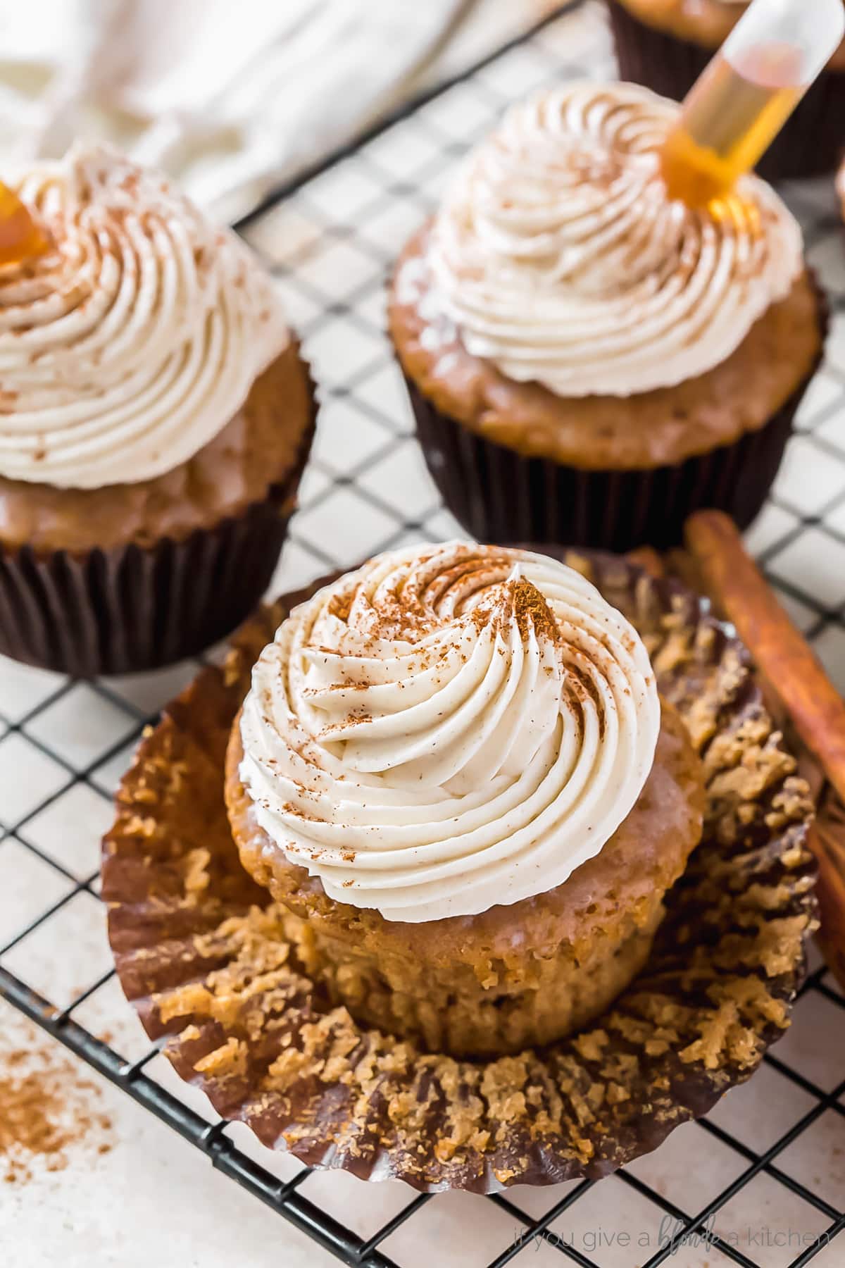 buttered rum cupcakes topped with rum frosting and cinnamon on unwrapped paper cupcake liner