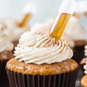 tops of buttered rum cupcakes with frosting and mini injector of rum inserted to cupcakes