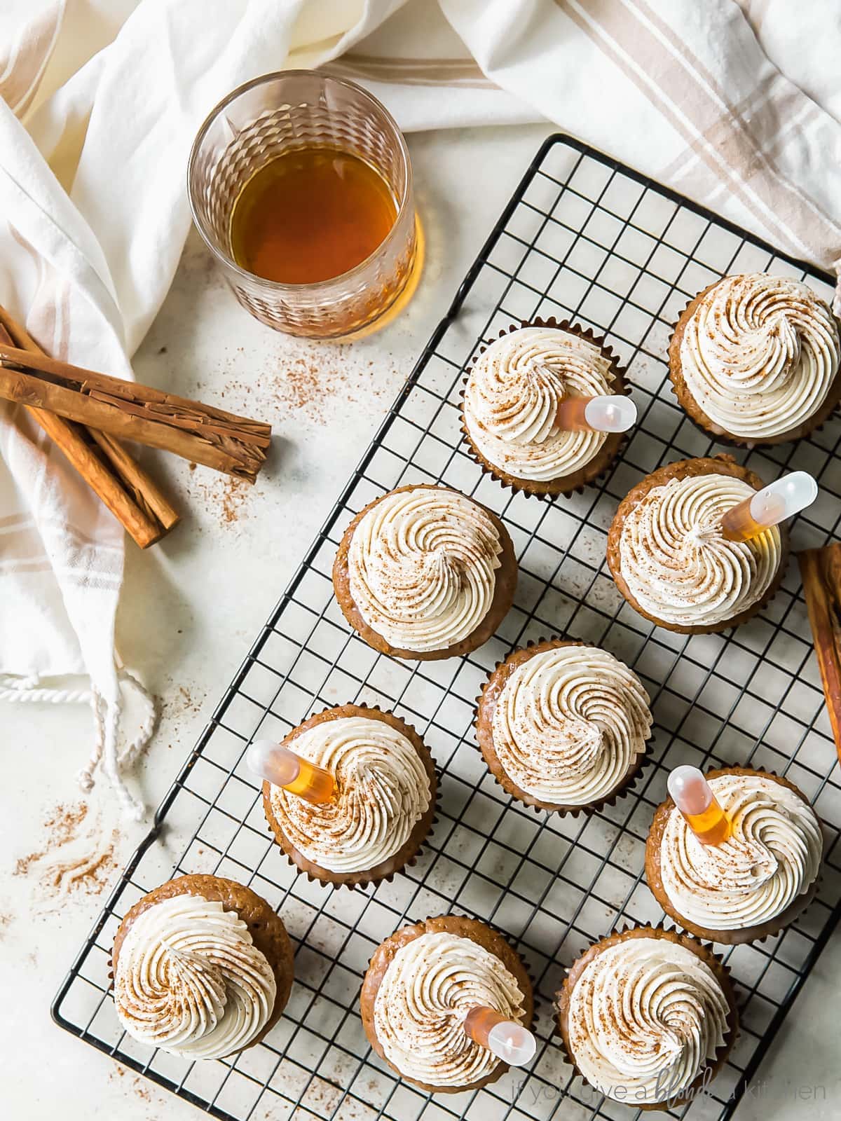 buttered rum cupcakes topped with frosting, cinnamon and rum on wire cooling rack