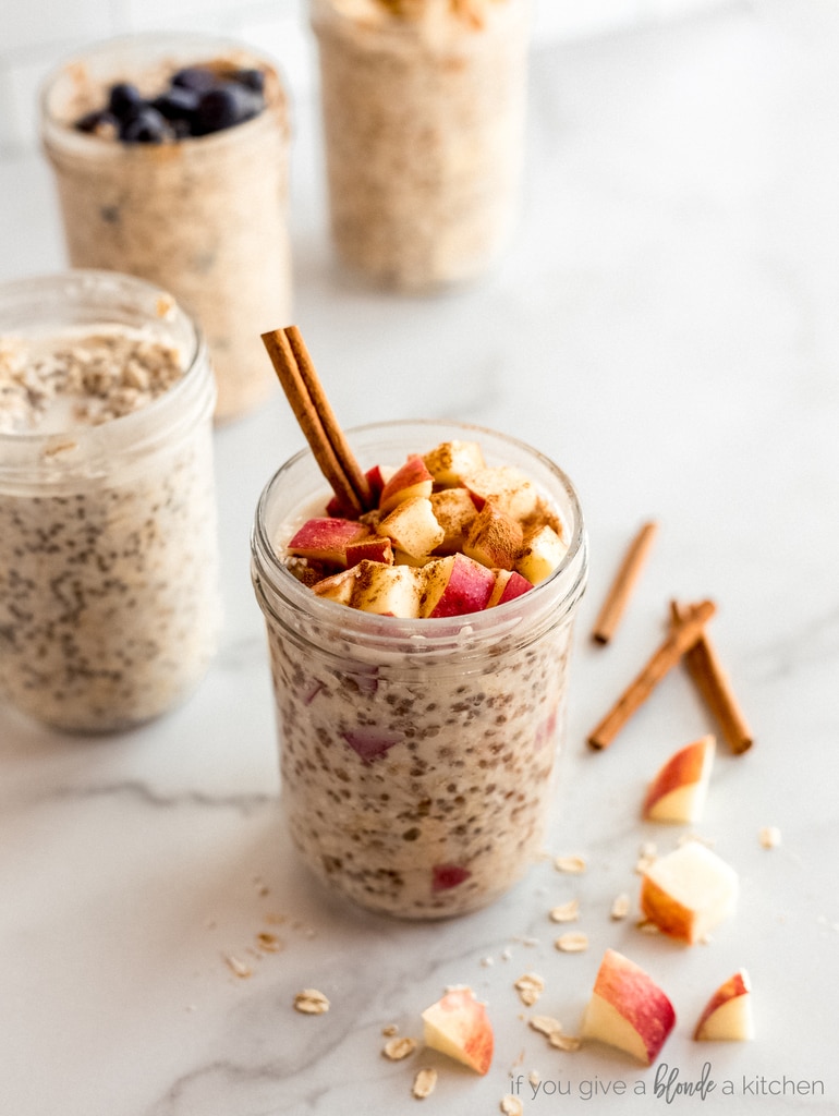 chopped apples and cinnamon stick on top of overnight oats in mason jar