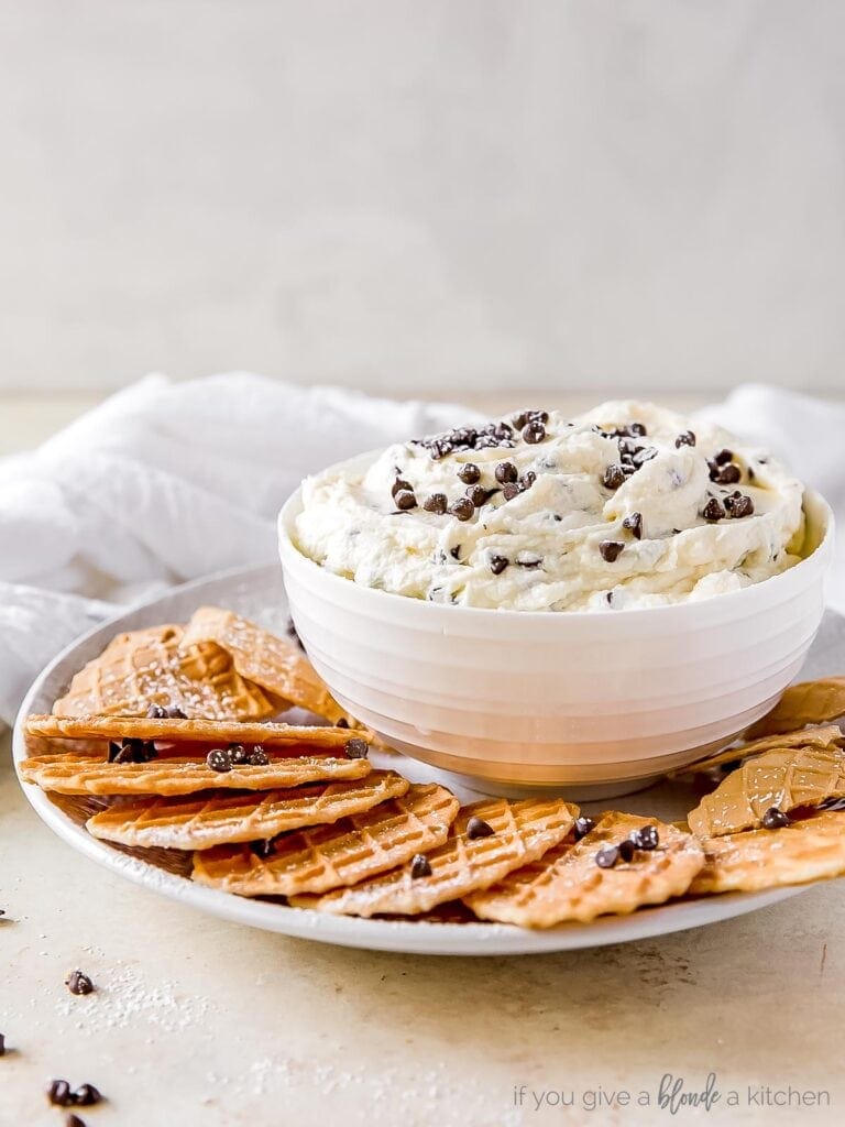 bowl of cannoli dip with mini chocolate chips on plate with pizzelle cookies