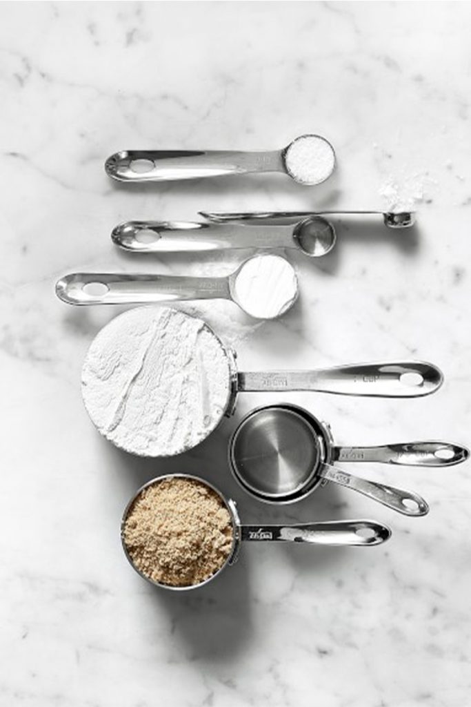 all clad measuring cups and spoons on marble surface