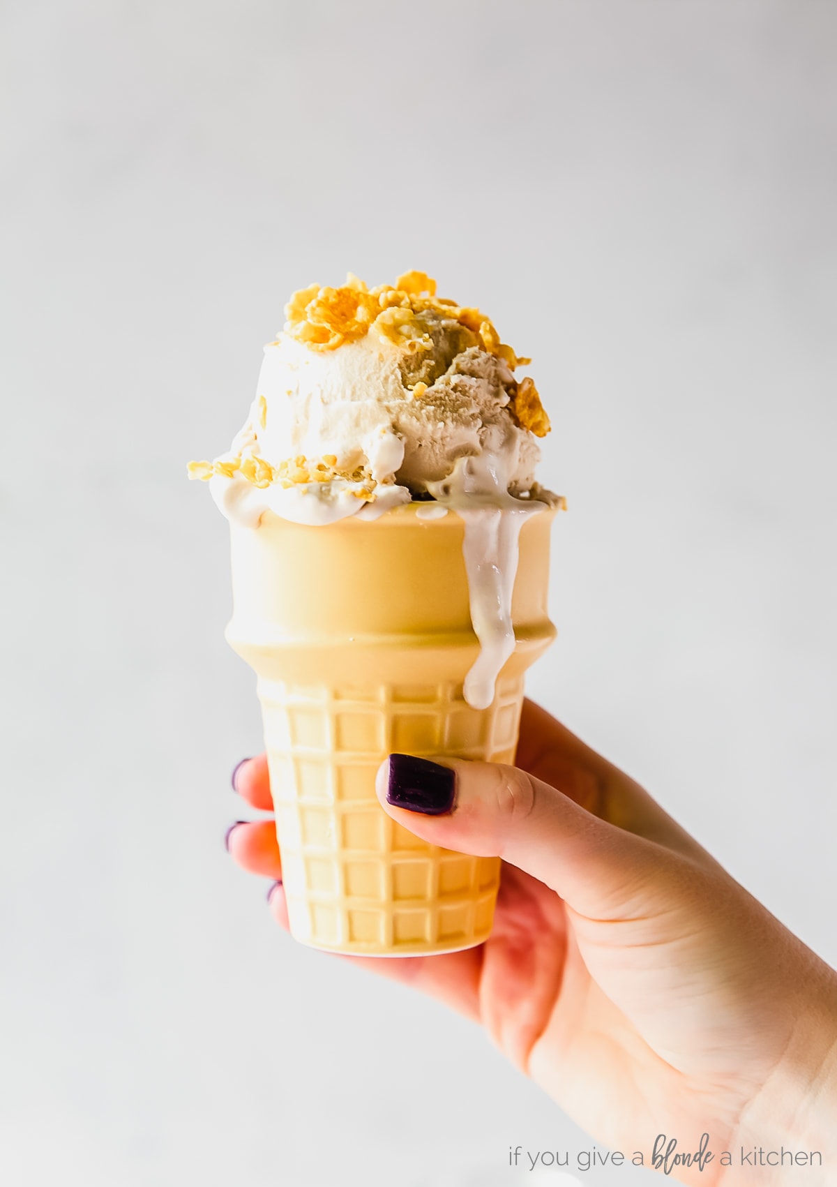 hand holding cake cone with cereal milk ice cream