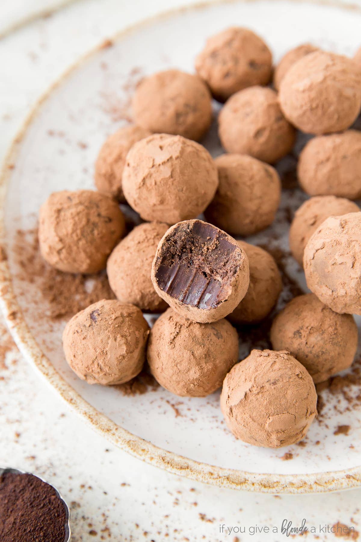 chocolate truffles coated in cocoa powder on plate; top truffle with bite out of it