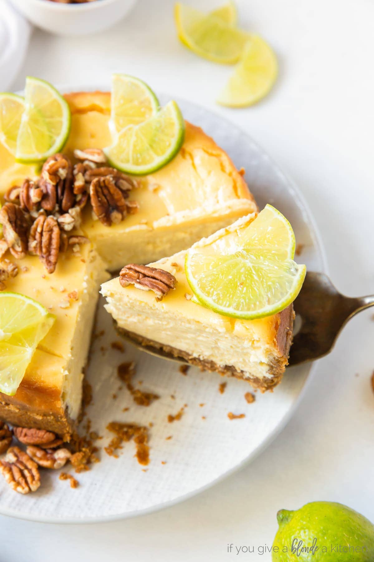 cake knife serving slice of lime curd cheesecake next to full cheesecake