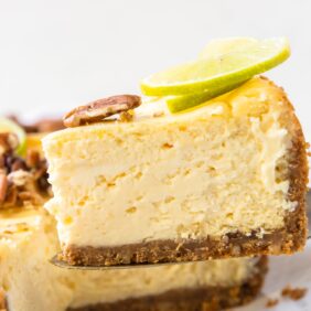thick slice of lime curd cheesecake on cake knife lifted up
