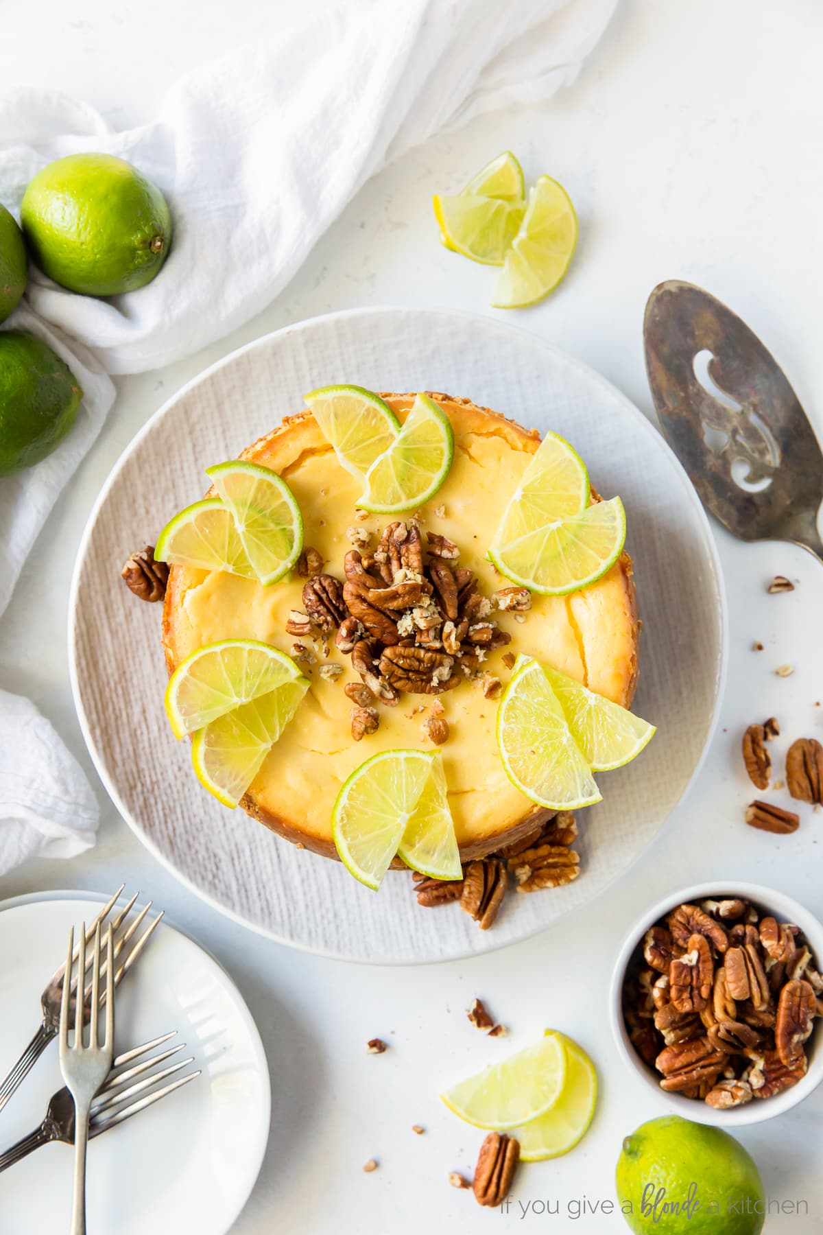 lime curd cheesecake garnished with lime slices and chopped pecans