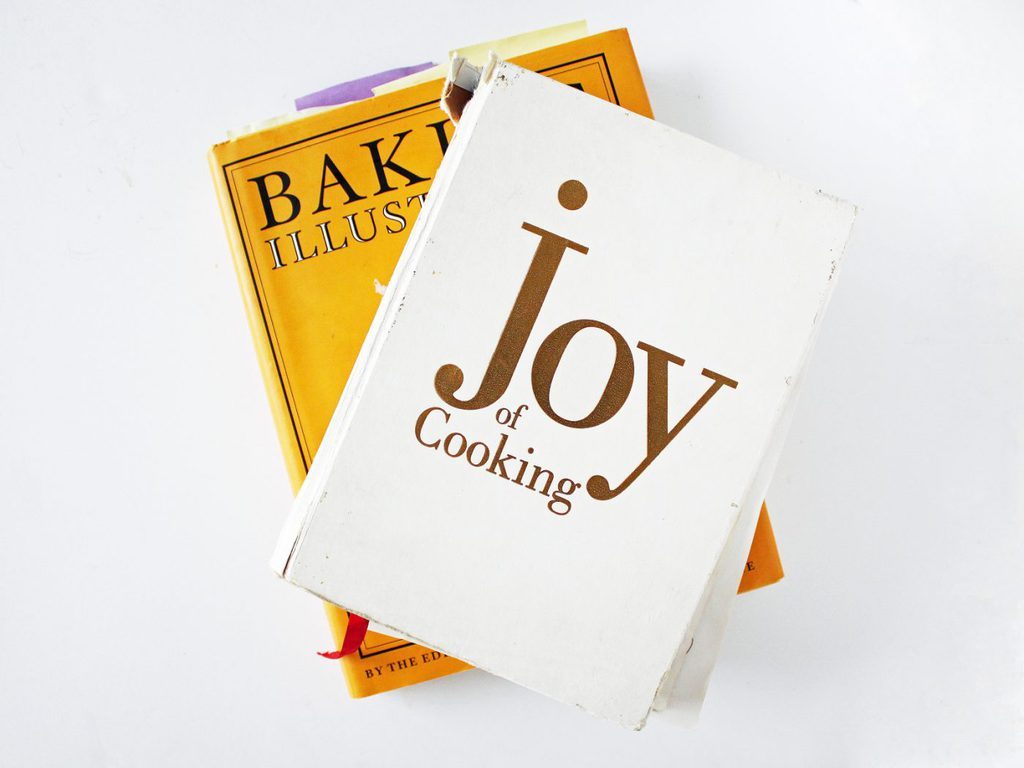 joy of cooking and baking illustrated cookbooks in stack.
