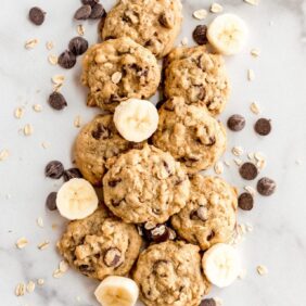 banana oatmeal cookies on parchment paper with slices of banana, chocolate chips and oats