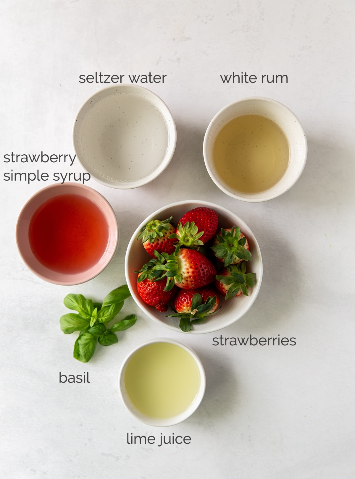 strawberry basil mojito ingredients in bowls labeled with text