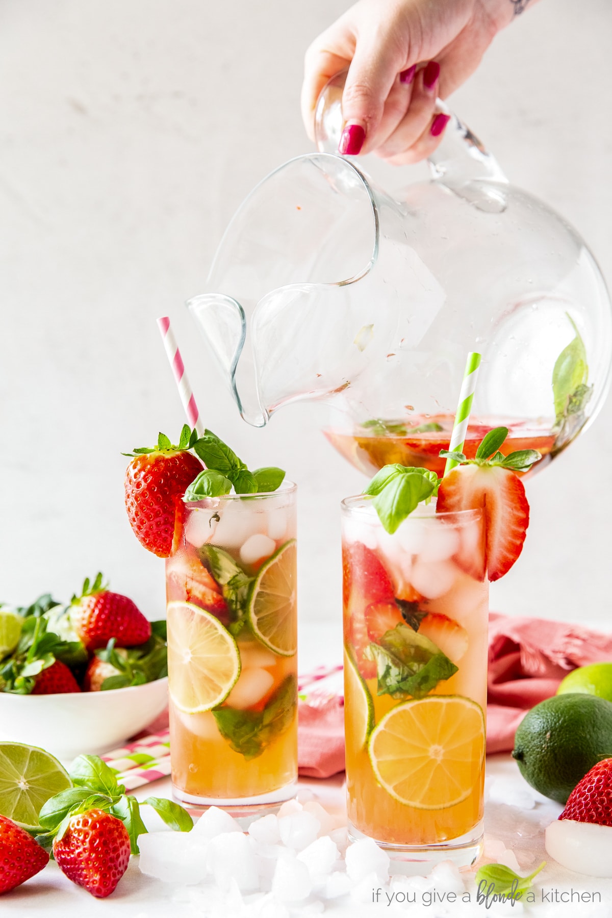glass pitcher pouring strawberry mojito into two glasses