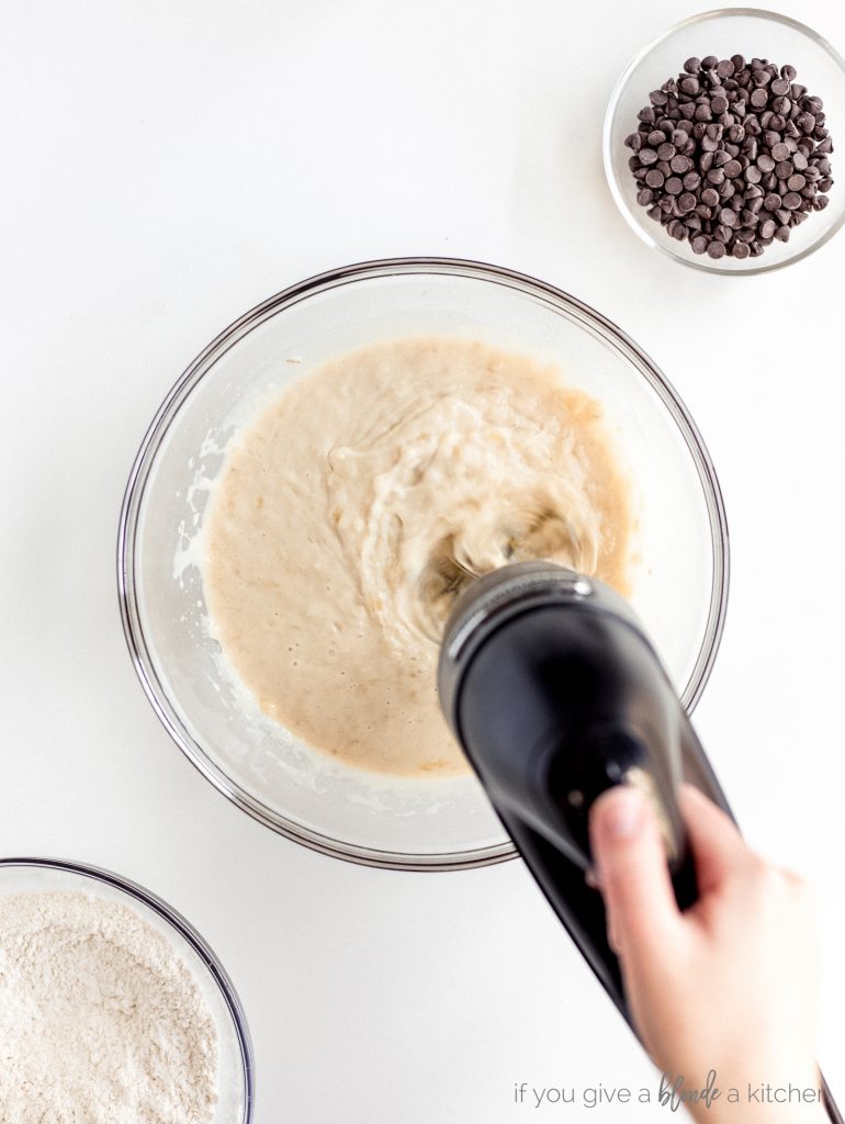 hand mixer combining smooth ingredients in bowl, small bowl of chocolate chips