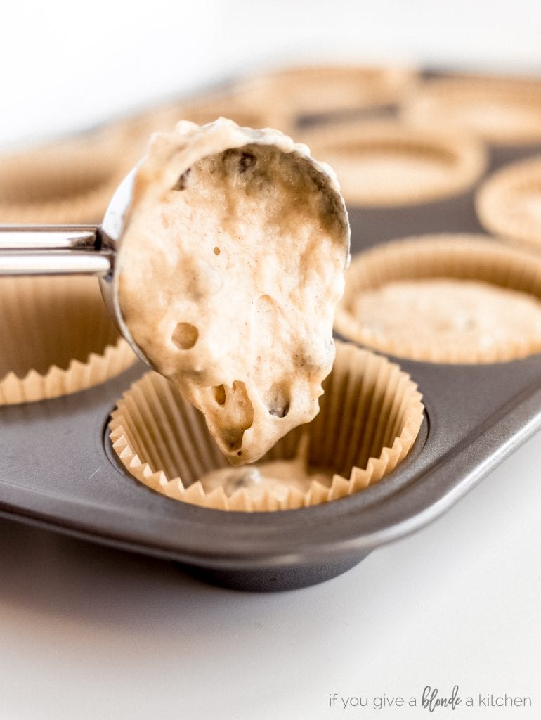 ice cream scoop pouring batter into muffin tin