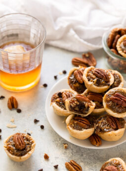 plate of mini derby pies next to glass of bourbon